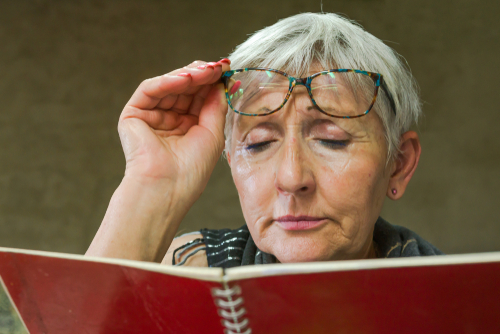 woman holding glasses while reading book